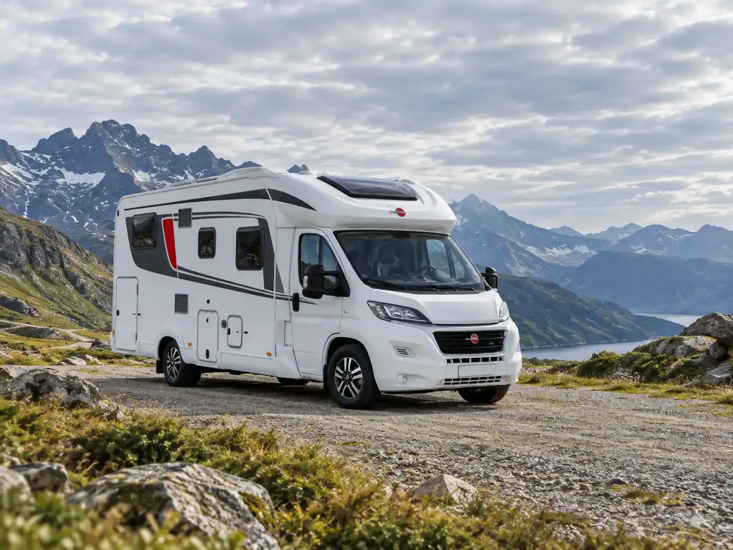 Wohnmobil auf einem freien Stellplatz vor Bergen und einem See