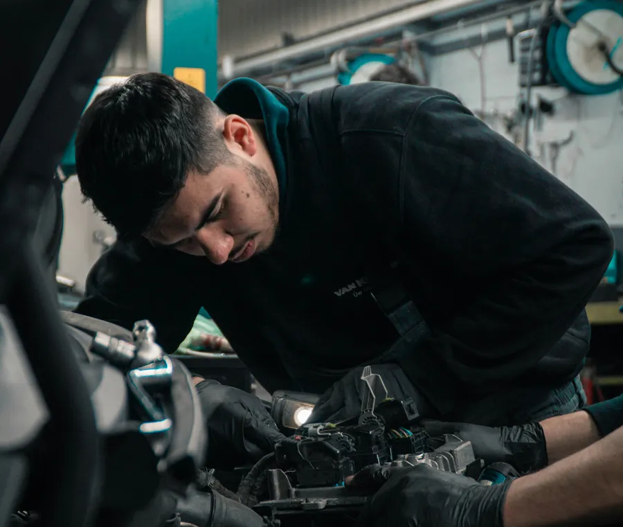 Mitarbeiter arbeitet in einer Reparaturwerkstatt an einem Fahrzeug