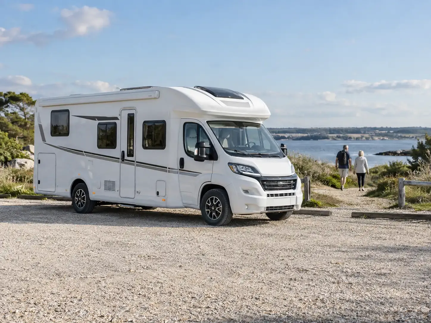 Wohnmobil am Wasser, während zwei Reisende einen Spaziergang machen